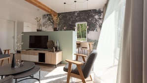 A modern living room with a TV, wooden furniture, and a large window. - Hofstede Moesbosch l Kloeg Collection (Koudekerke)