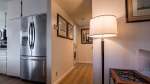 Eine moderne Küche mit einem Edelstahl-Kühlschrank, Holzboden und einem Tisch mit einer Lampe.