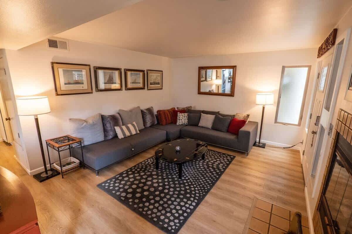 Ein Wohnzimmer mit einem Ecksofa, einem Couchtisch und einem gemusterten Teppich.