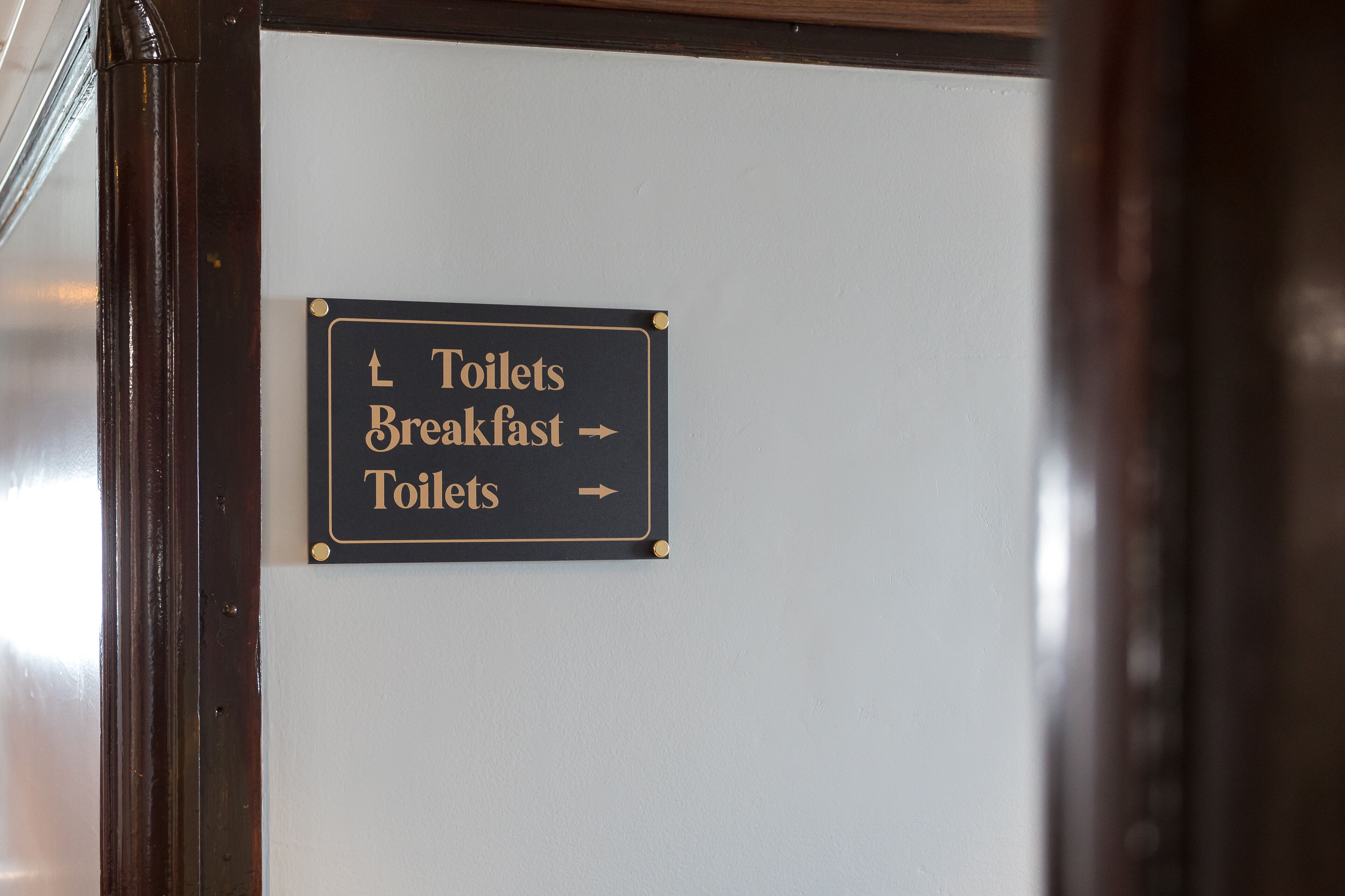 A sign indicating the direction to toilets and breakfast.