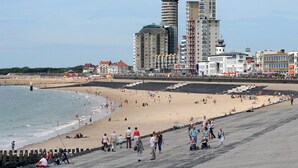 A beach with people, a promenade, and buildings in the background. - Hotelboot Koningin Emma Kloeg Collection (Vlissingen)