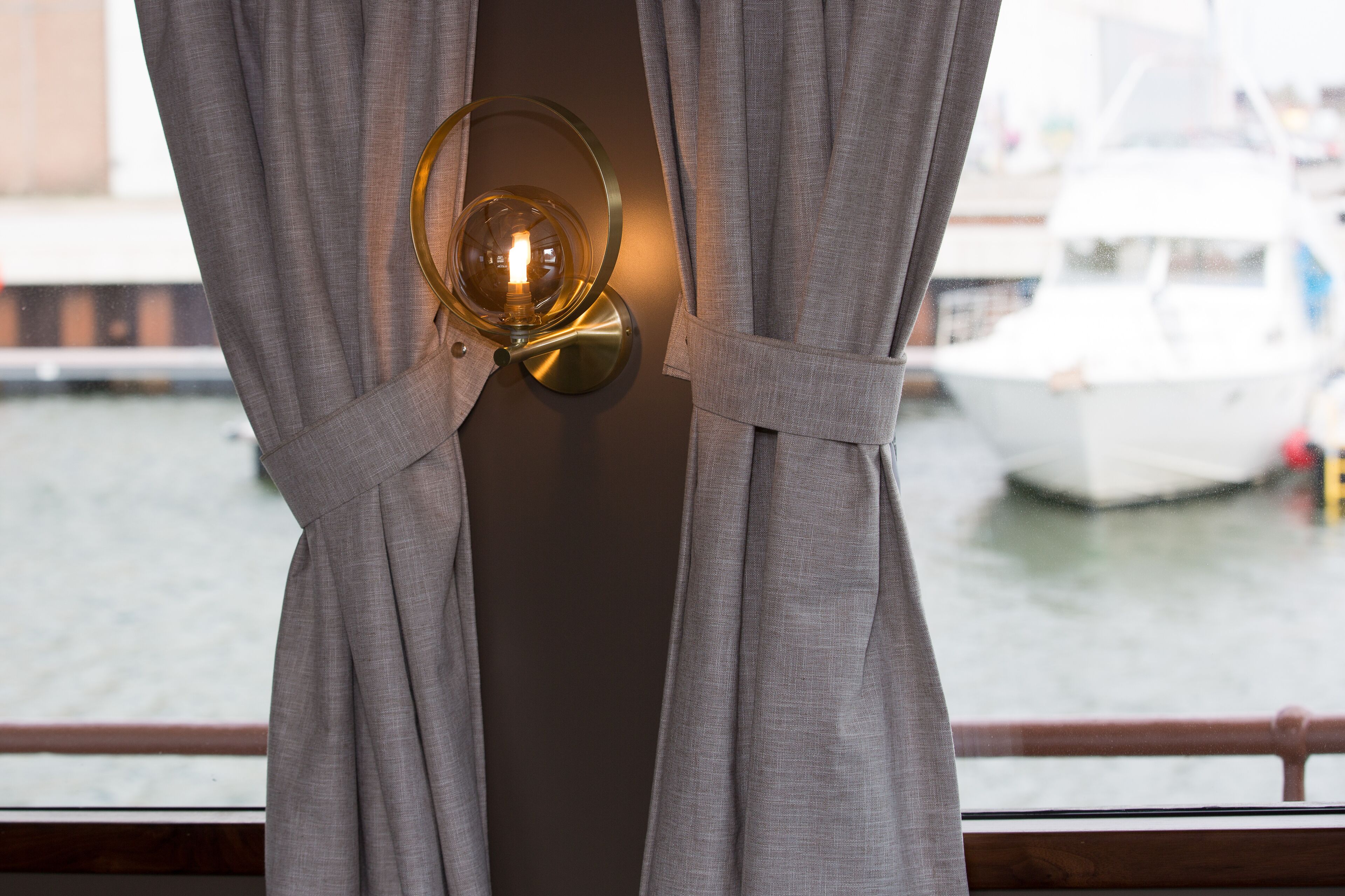 A window with grey curtains and a wall-mounted light fixture.