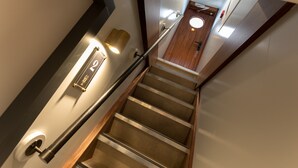 A modern staircase with a handrail, a wall-mounted light, and a wooden door at the top. - Hotelboot Koningin Emma Kloeg Collection (Vlissingen)
