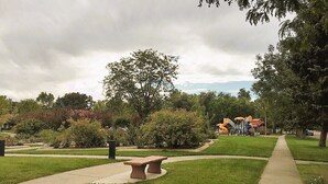 A park with a paved walkway, benches, and trees. - Exquisitely Restored Boulder County Victorian Cottage, c1906 🏡 (Longmont)