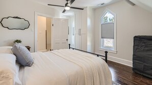 A bedroom with a bed, a ceiling fan, a large window, and a wardrobe. - Exquisitely Restored Boulder County Victorian Cottage, c1906 🏡 (Longmont)