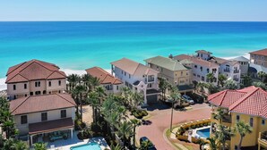 Una zona residencial costera con varias casas, una piscina y vista despejada al océano.