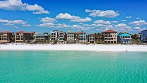 Un hotel frente a la playa con varias construcciones, una playa de arena y agua turquesa cristalina.