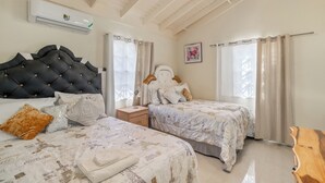 Ein Schlafzimmer mit zwei Betten, einem Nachttisch, einer Klimaanlage und einem Holzkopfstück.