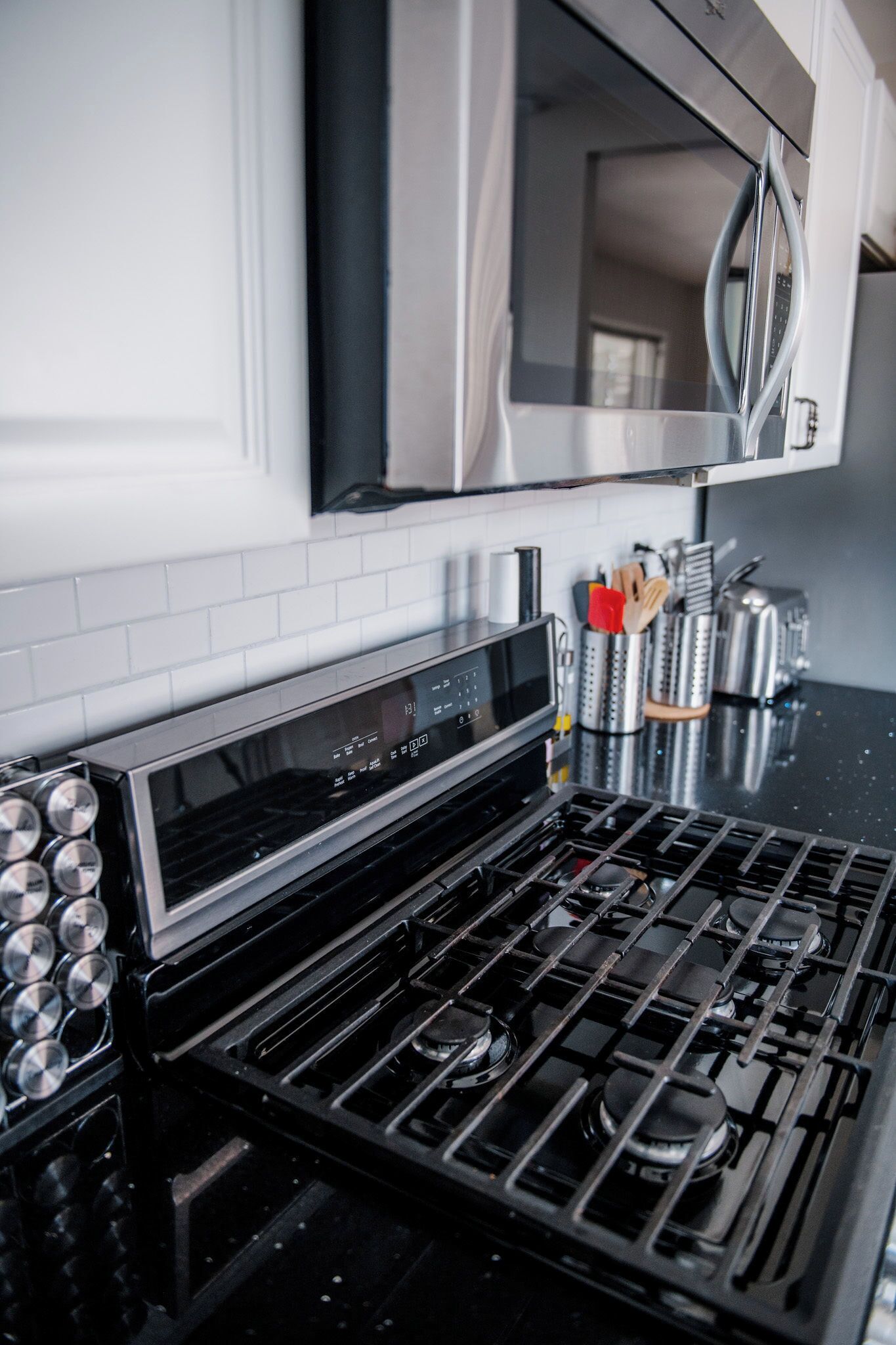 A kitchen with a stainless steel stove, a microwave above it, and a tiled backsplash.