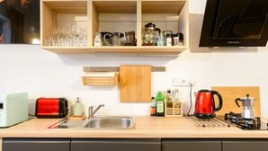 Una cocina moderna con microondas integrado, un tostador rojo, un lavamanos y una cafetera.