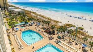 Un resort con una piscina grande, acceso a la playa y vistas al océano.