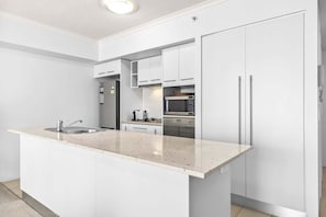 A modern kitchen with white cabinetry, a central island, stainless steel appliances, and a tiled backsplash.