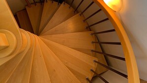 Eine Wendeltreppe aus Holz mit Geländer und einer an der Wand befestigten Leuchte.