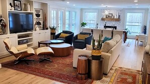 A spacious living room with a flat-screen TV, multiple seating options including a sofa and chairs, a coffee table, and a decorative rug. - Corporate rental, great for families in Energy Corridor. (Houston)