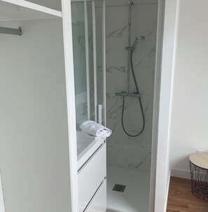 Une salle de bain moderne avec une douche à parois de verre, une serviette blanche posée sur le comptoir et un plancher en bois.