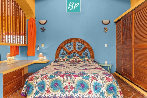 Une chambre à coucher avec un lit, une tête de lit en bois et un mur bleu.