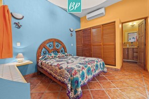Une chambre à coucher avec un lit, une table de chevet, une armoire et une salle de bain visible à travers une porte ouverte.