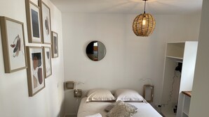 A bedroom with a bed, white pillows, a round mirror, and a hanging light fixture. - LE POULORIO TERRASSE - T3 RDC - 2 salles de douches  * ByLocly * (Lorient)