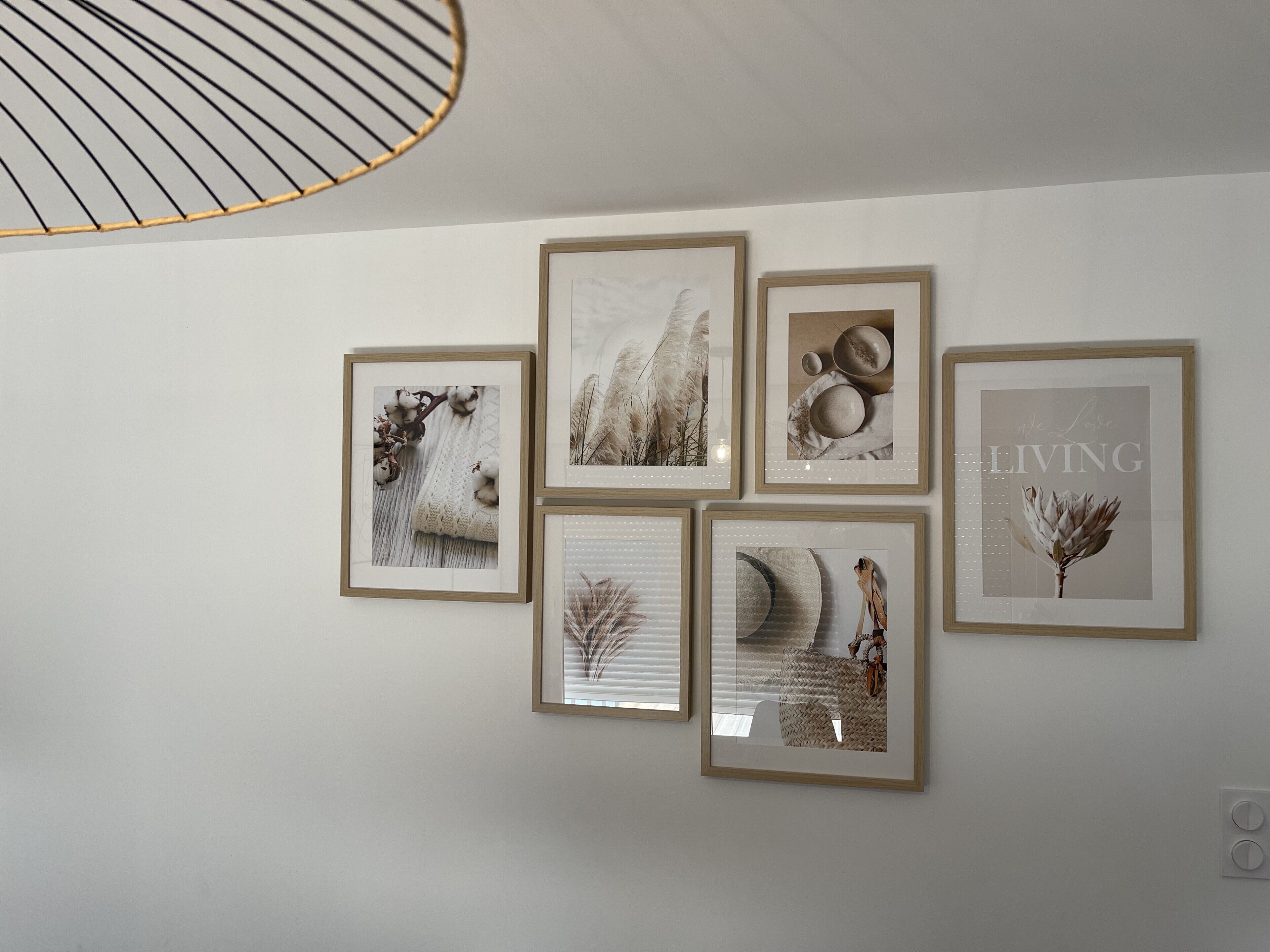 Eine Wand mit sechs gerahmten Kunstwerken, einer Deckenleuchte und einem Thermostat.