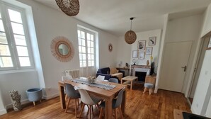 Un vaste espace de vie comprenant une table à manger en bois, des chaises, un canapé et une cheminée.