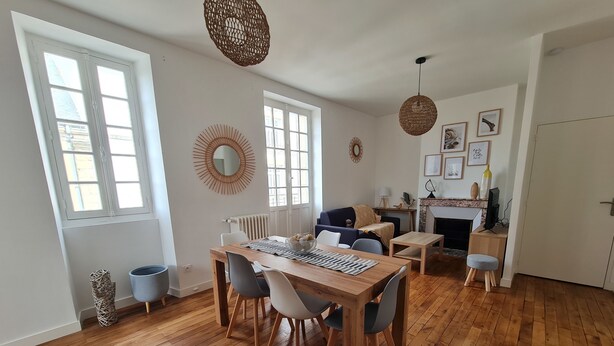 Un vaste espace de vie comprenant une table à manger en bois, des chaises et une cheminée.