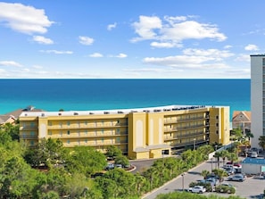 Ein mehrstöckiges Hotel mit Balkonen, einem Parkplatz und Blick aufs Meer.