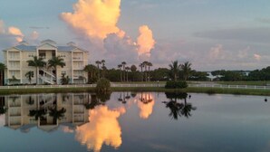 A hotel with a reflection in a calm body of water, surrounded by palm trees and a white fence. - 5 Star Resort Style Luxury Condo top floor bay views 3 miles to Beach (Bradenton)