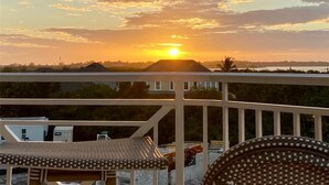A sunset view from a balcony with a railing, a building in the background, and a clear sky. - 5 Star Resort Style Luxury Condo top floor bay views 3 miles to Beach (Bradenton)