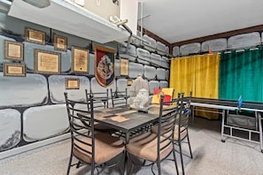 A room with a chess table, chairs, a trophy, and a wall decorated with plaques.