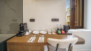 Una mesa de madera con cafetera, platos, cubiertos, vasos y una tetera.