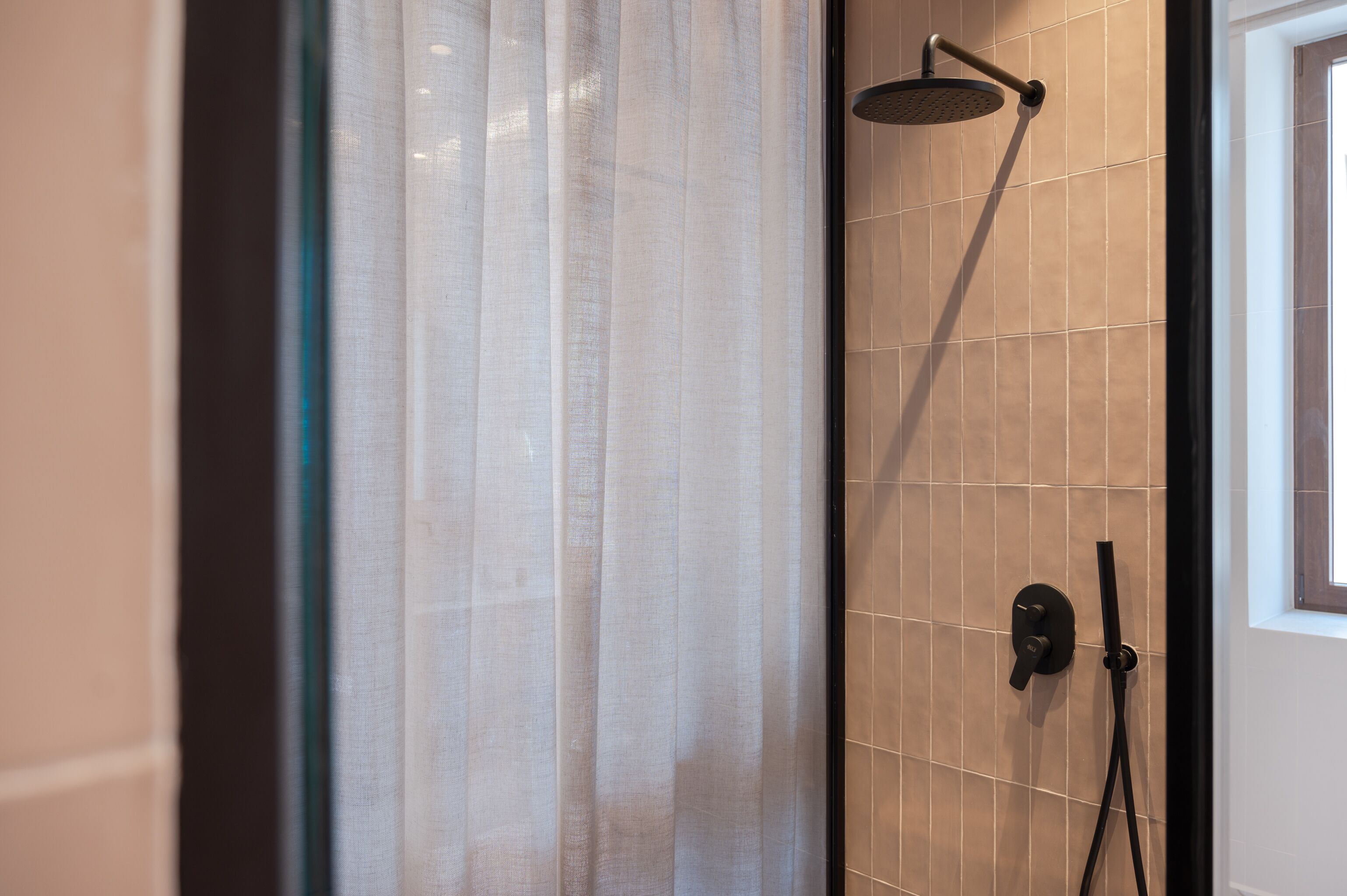 Un bagno con doccia, tenda e finestra.
