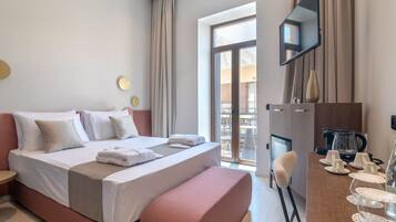 A hotel room with a large bed, a desk with a coffee maker, and a TV on the wall.