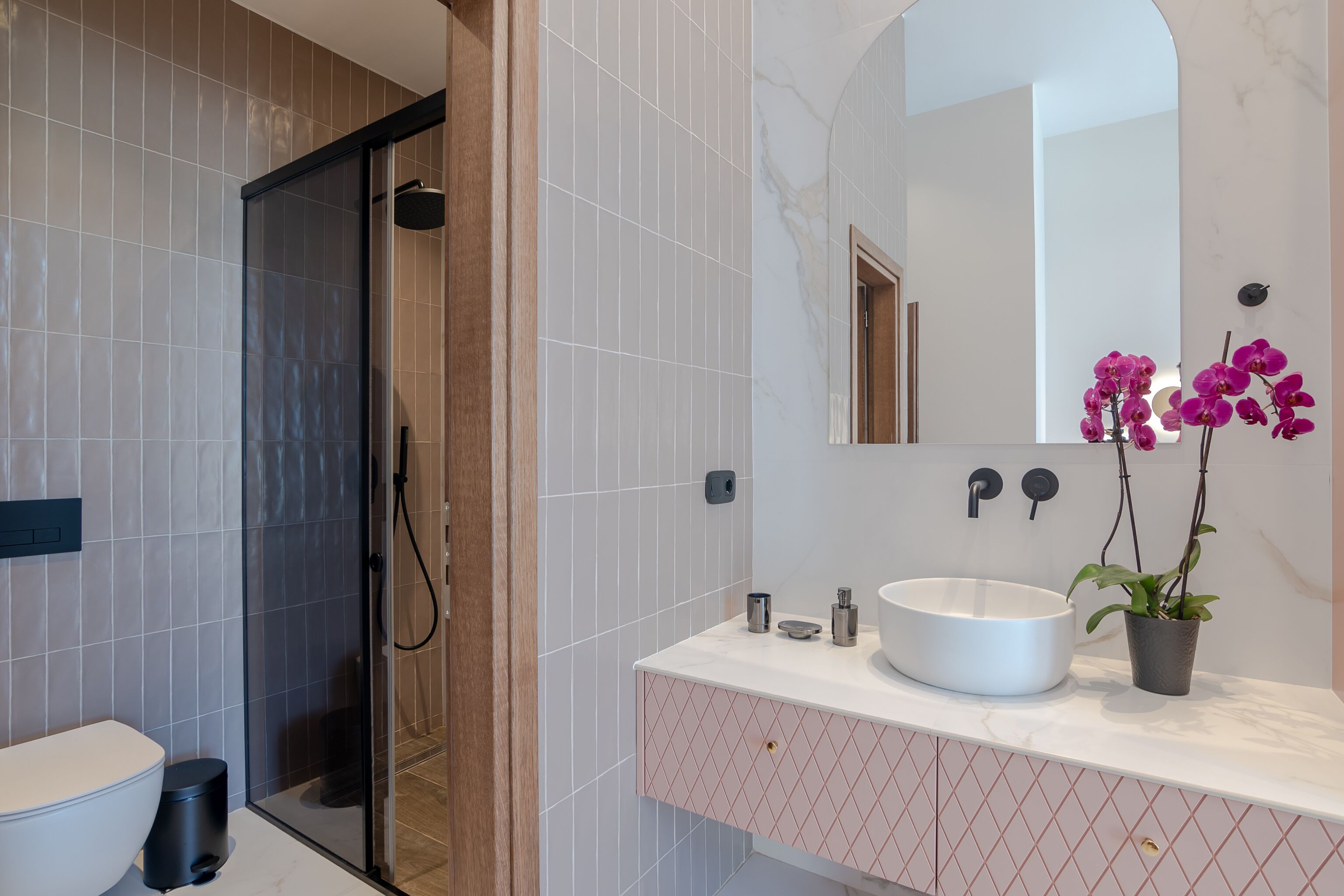 A modern bathroom with a glass-enclosed shower, a white sink, and a mirror above it.