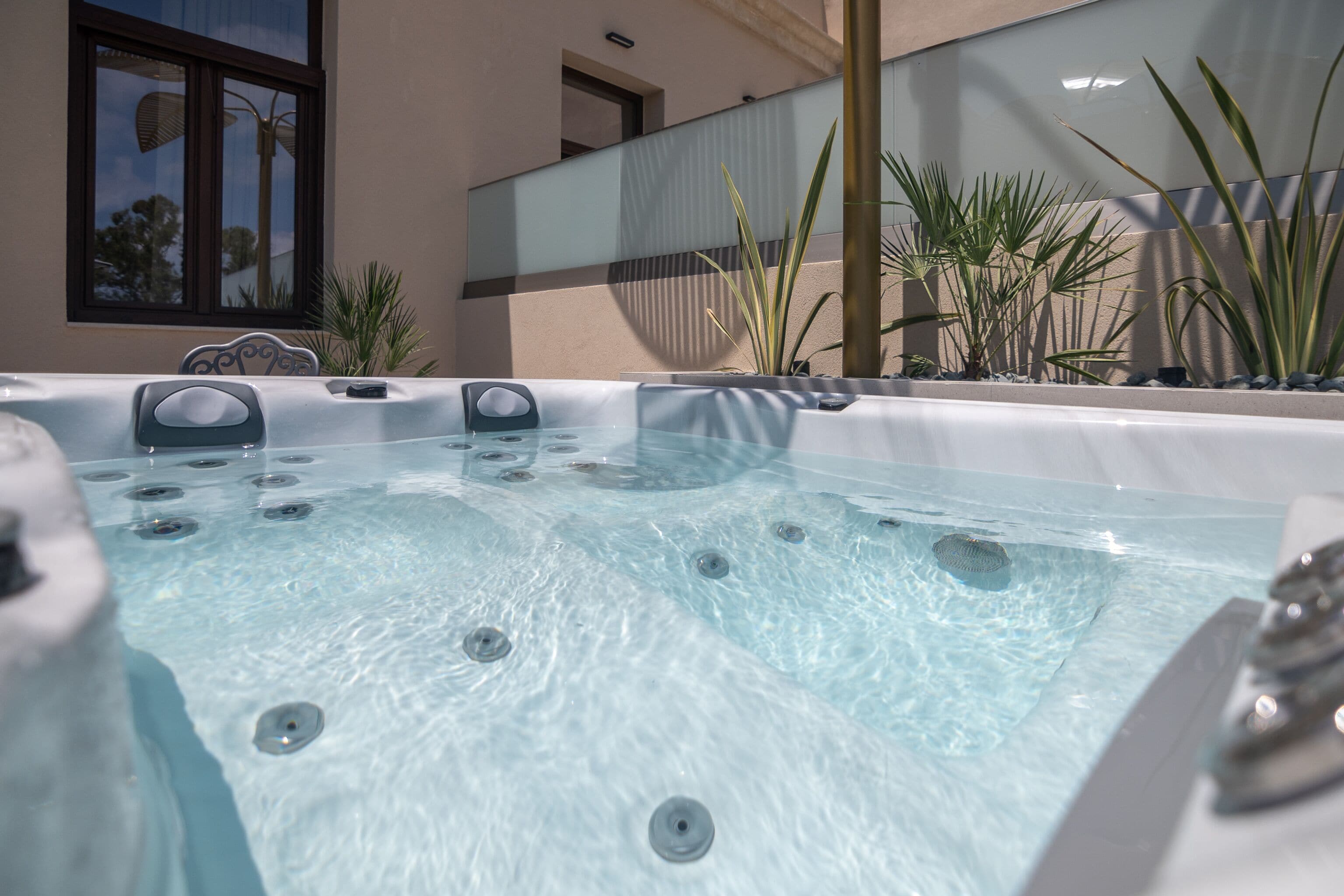 A hot tub area with multiple tubs, a glass partition, and potted plants.