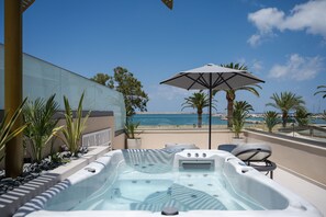 A hot tub with a view of the beach and ocean, surrounded by palm trees and potted plants. - Omma Suites (Rethymno)