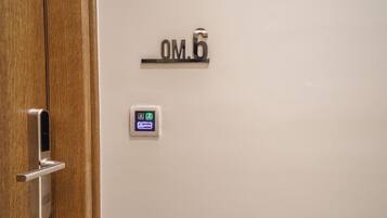 Una puerta con una cerradura digital y un cartel encima que dice 'OM.6'.