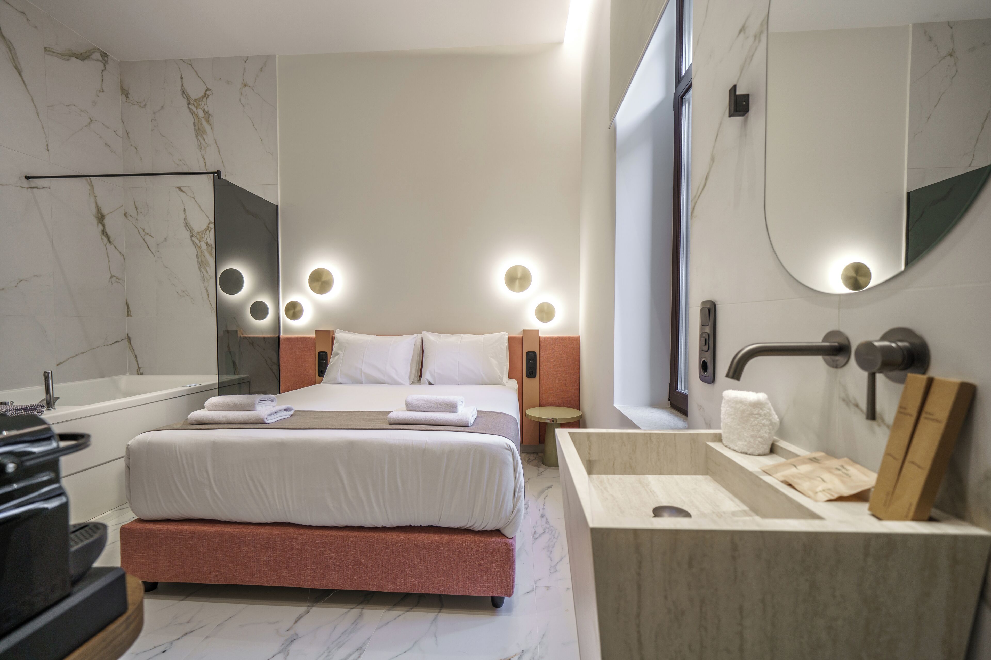 Habitación de hotel moderna con cama, un espejo grande, lavabo integrado y bañera.