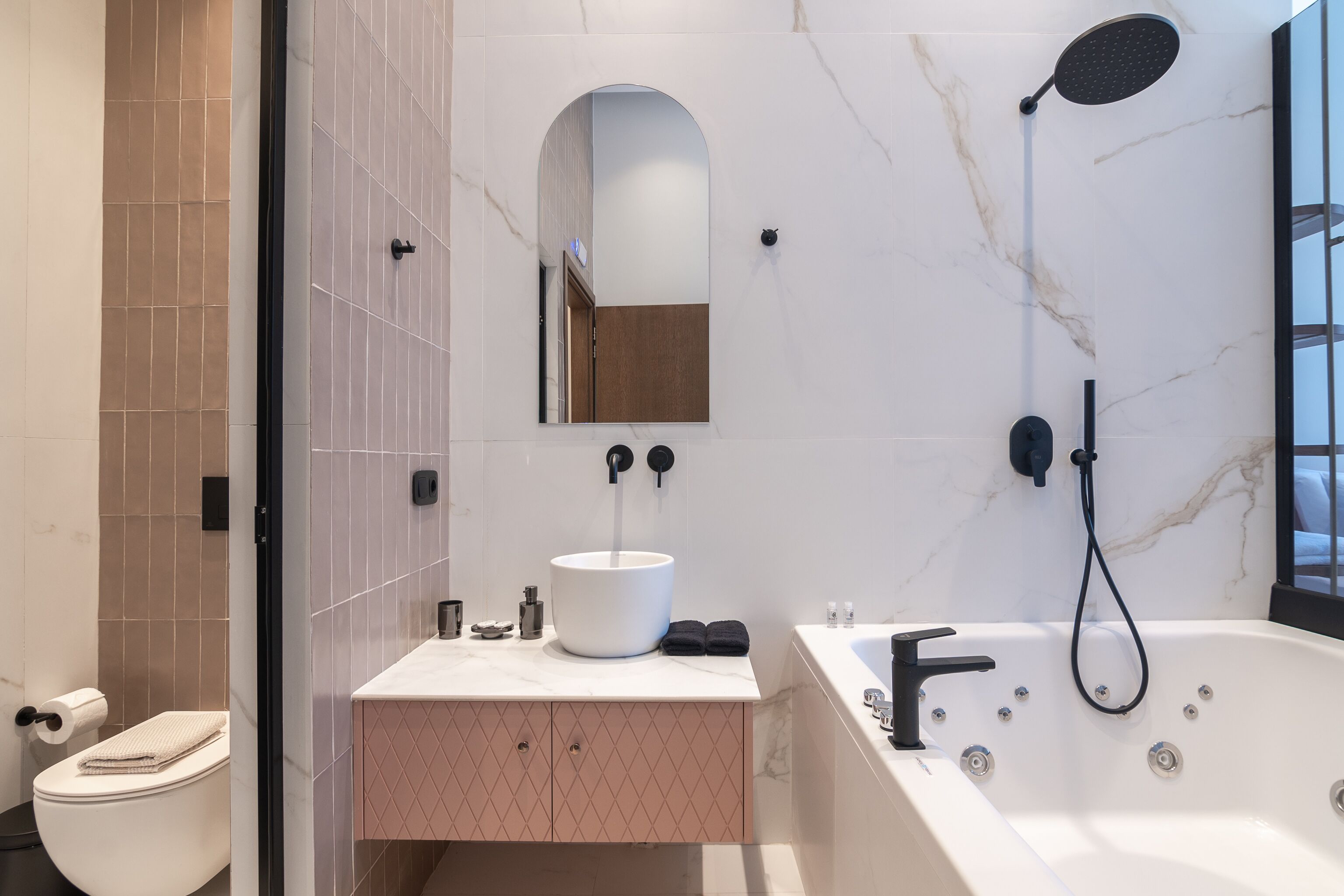 A modern bathroom with a white sink, a large mirror, a shower, and a toilet.