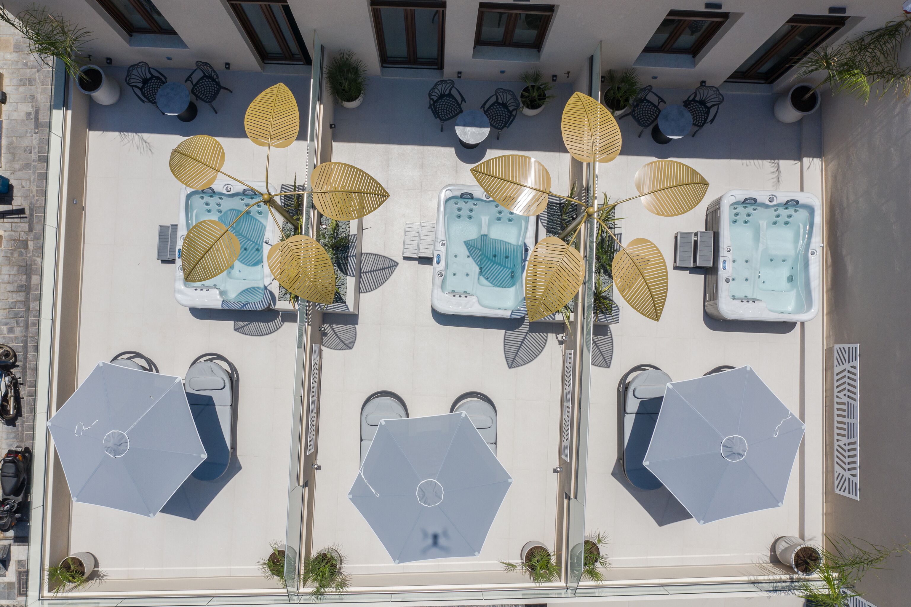 Een terras op het dak met verschillende zitgedeeltes, waaronder hexagonale tafels en stoelen, omringd door grote parasols.