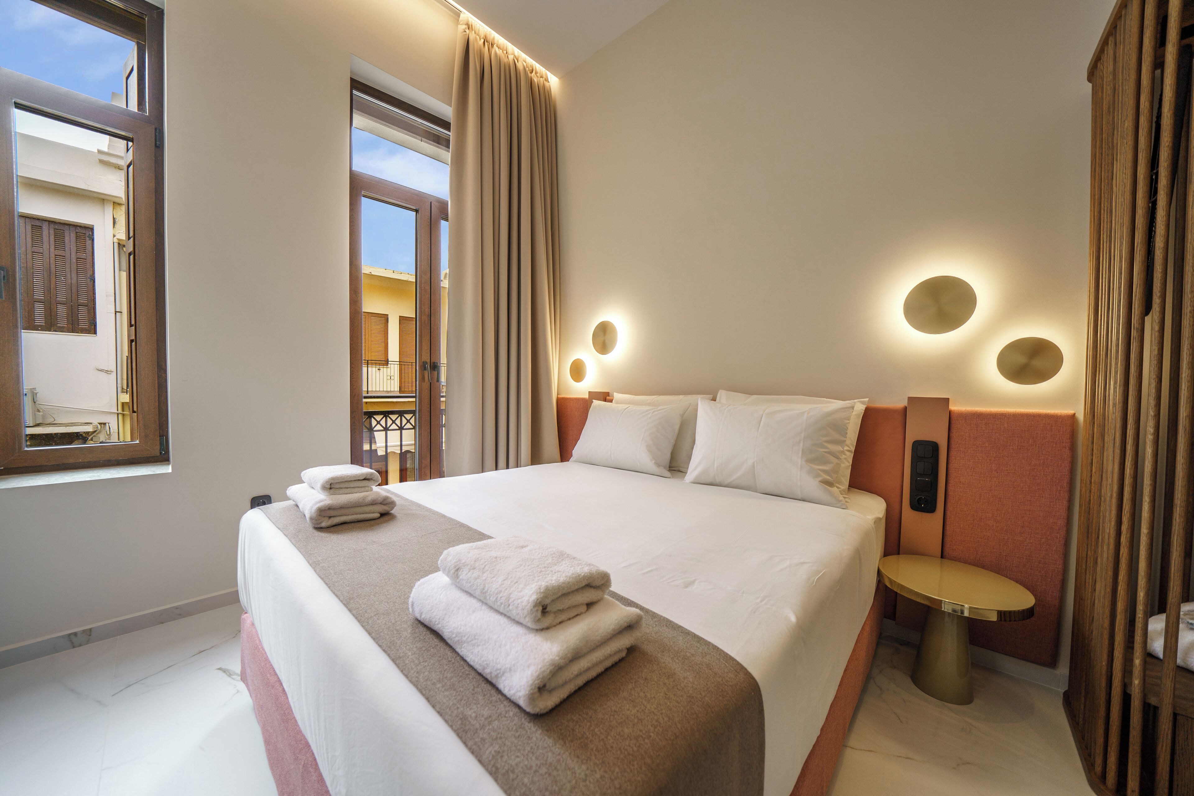 Habitació d'hotel amb un llit gran, una taula de nit, una finestra i vistes a l'exterior.