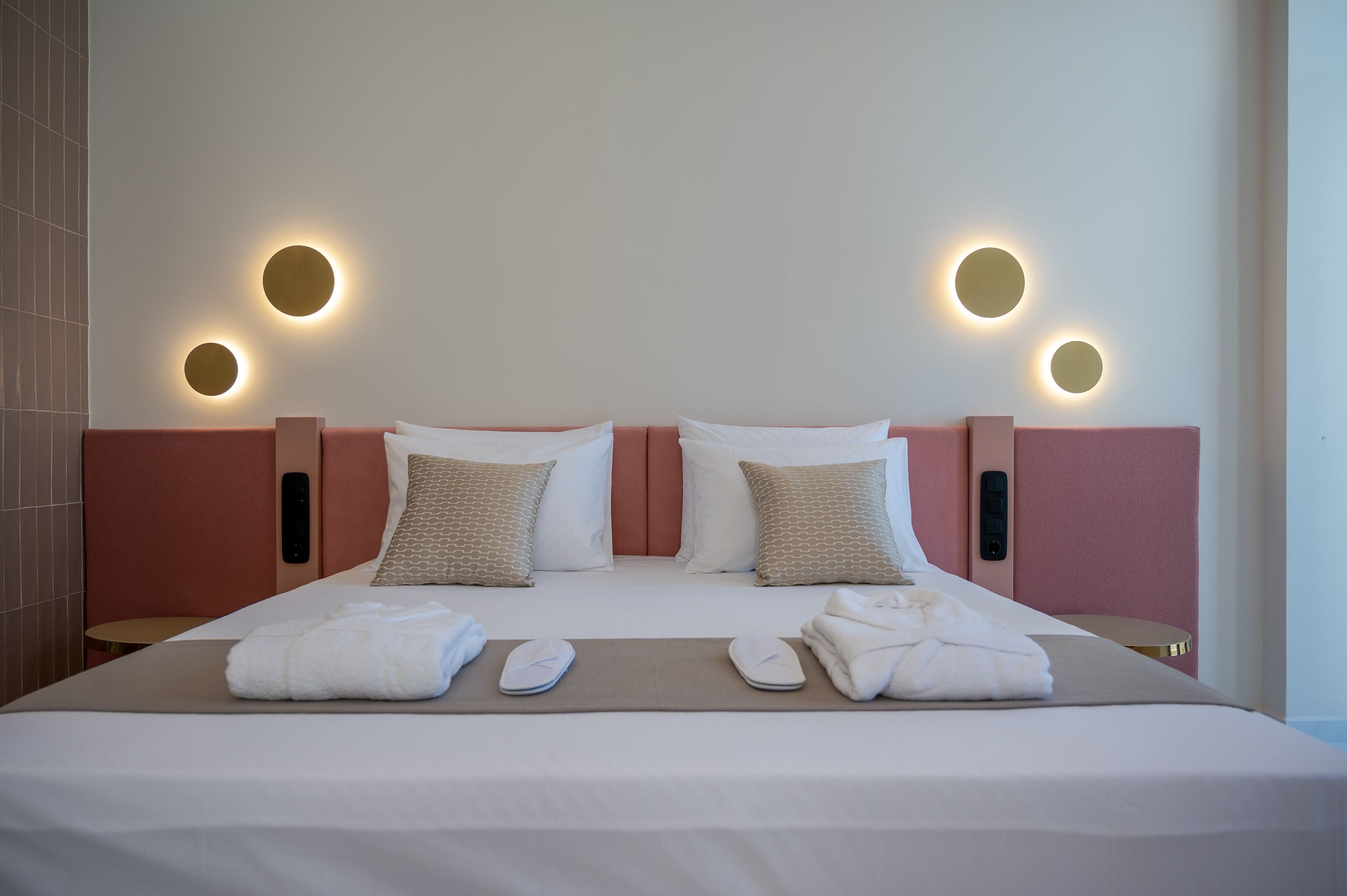 A hotel room with a large bed, two bedside tables, a wall-mounted light fixture, and a small round table.