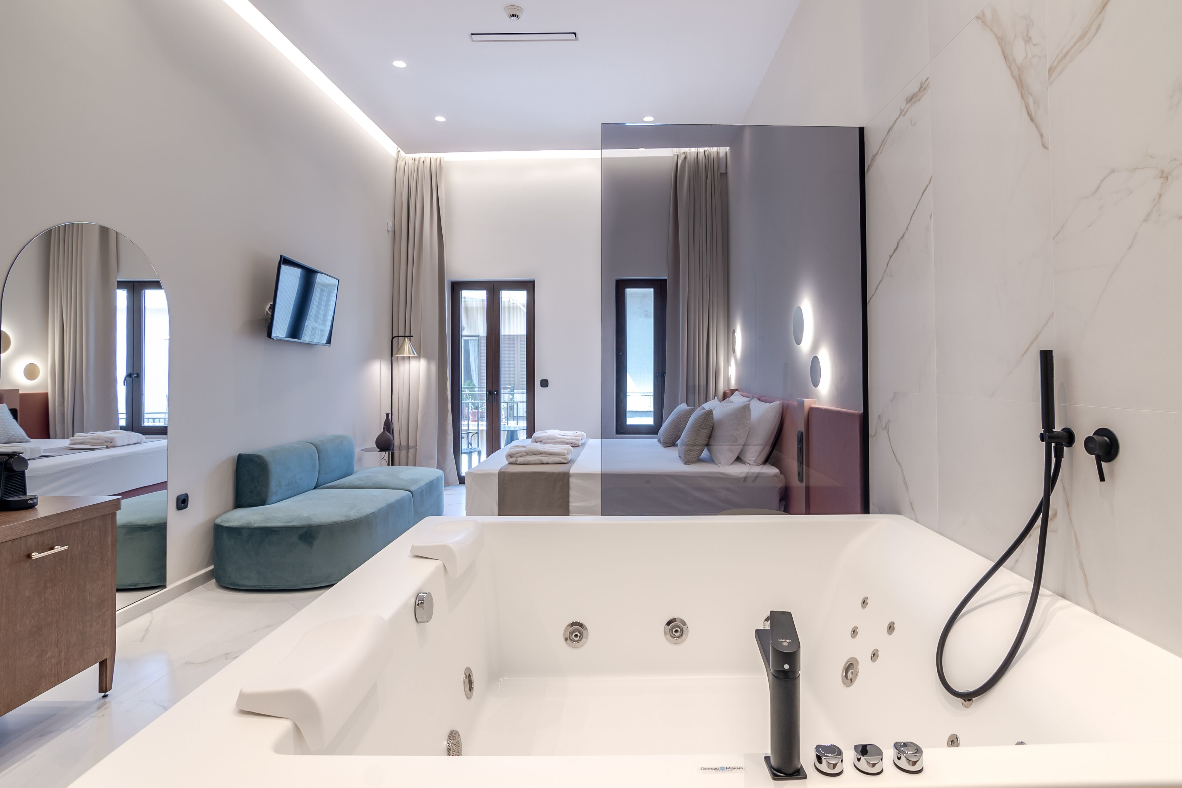 Een moderne hotelkamer met een groot bad, een bank, een bed en een televisie.