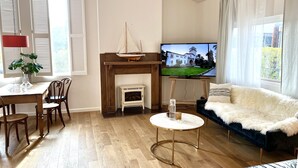 Un salon avec une cheminée, un téléviseur, un coin repas avec des chaises et un canapé.