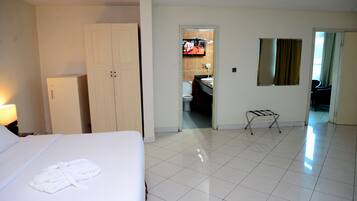 A hotel room with a bed, a wardrobe, a mirror, and a view into the bathroom.
