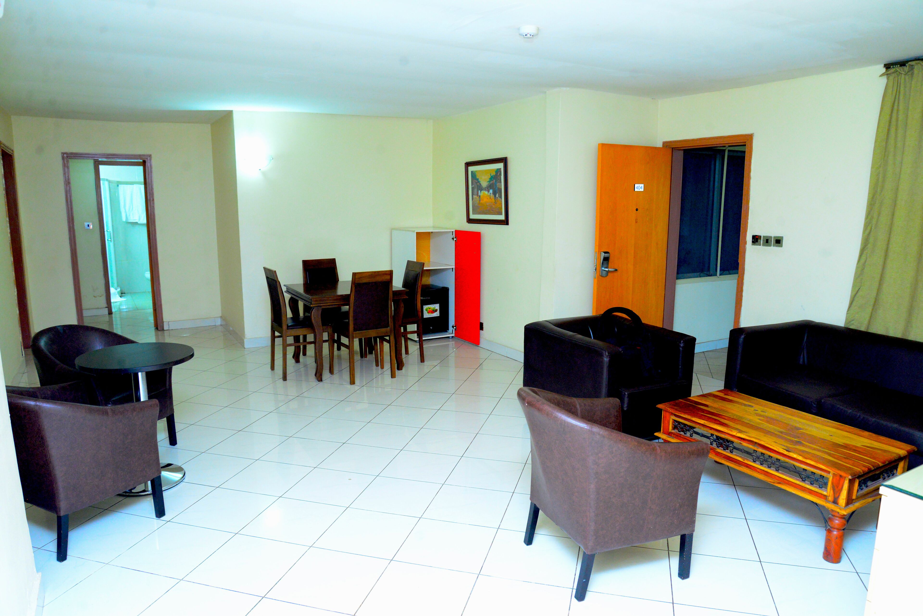 A living room with a dining area, a sofa, a coffee table, and a door leading to another room.