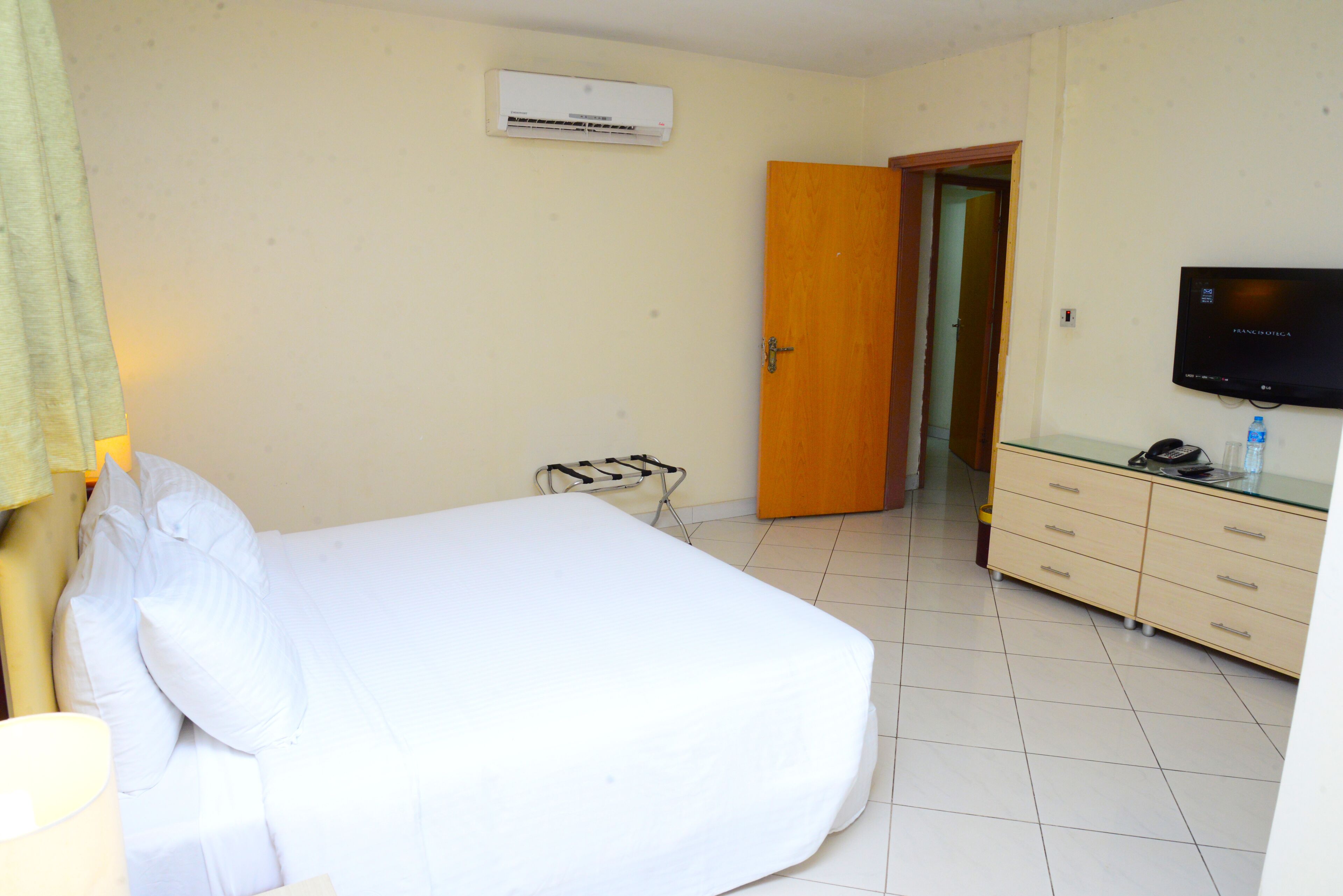 Une chambre d’hôtel équipée d’un lit, d’une télévision, d’un mini-bar et d’une porte donnant sur une autre pièce.