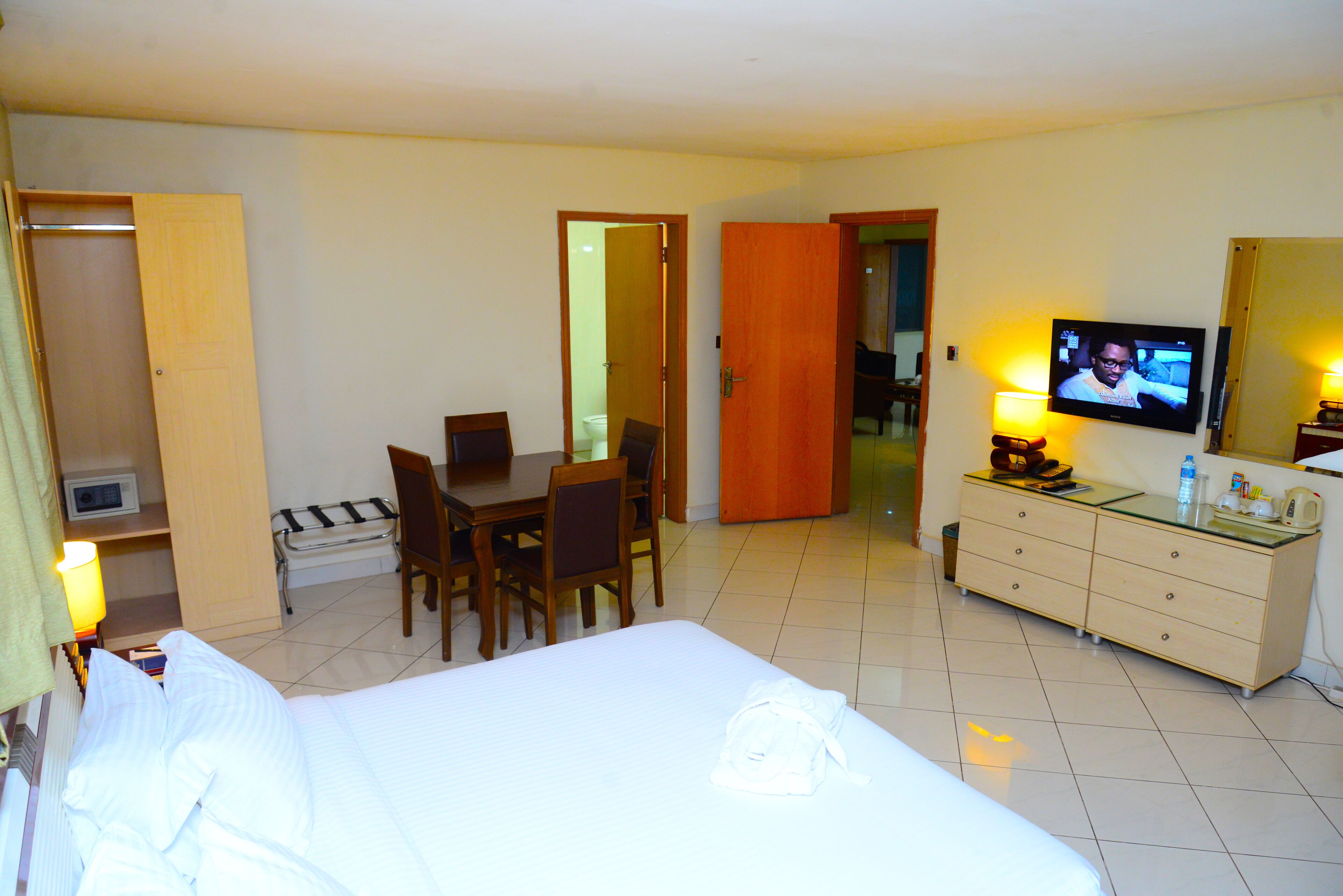 A hotel room with a bed, a desk, a chair, a television, and a dresser.