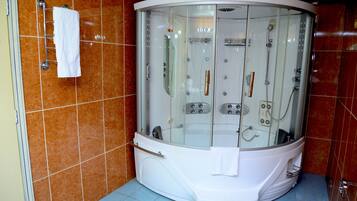 A modern bathroom with a glass-enclosed jacuzzi, a white towel rack, and a tiled floor.