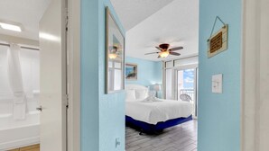 Un dormitorio con cama, ventilador de techo y vistas al exterior.