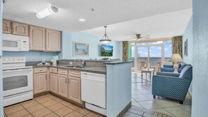 A kitchen with a microwave, stove, and dishwasher, a dining area with a table and chairs, and a view of the outdoors. - Stunning Views in Atlantica Resort (Myrtle Beach)